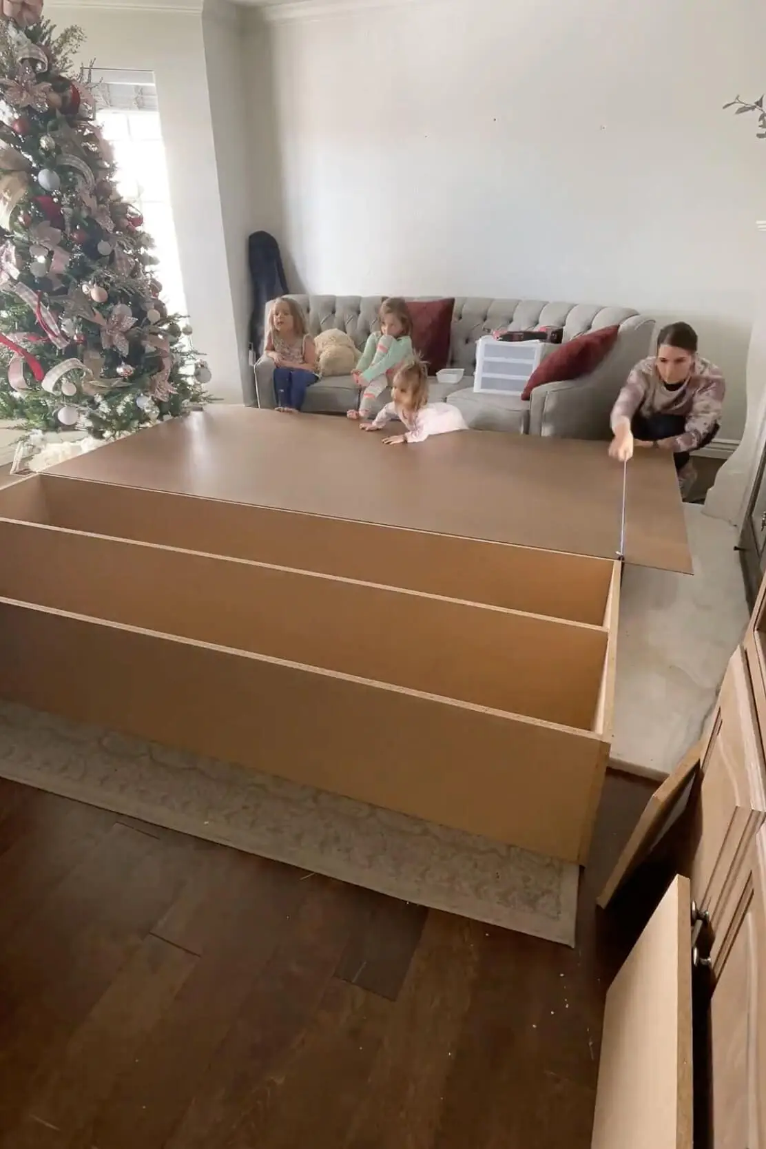 Securing the back panel of a custom built-in storage unit with a power drill, making sure the structure is solid.